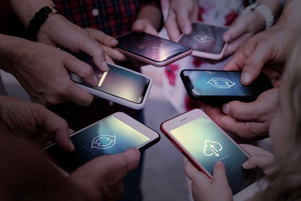 Hands holding smartphones together, each displaying syncing icons. The close-up conveys a sense of connectivity and shared digital interaction.