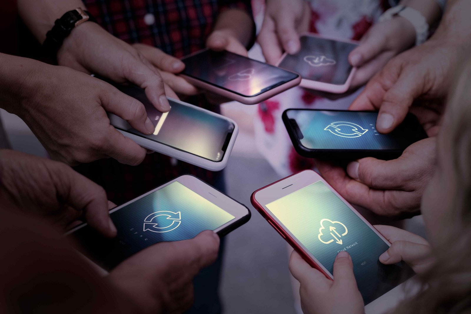 Hands holding smartphones together, each displaying syncing icons. The close-up conveys a sense of connectivity and shared digital interaction.